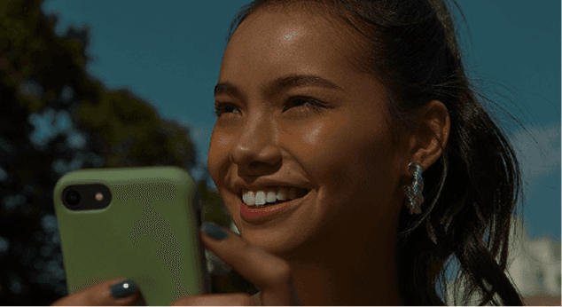 Pessoa em seu escritório mexendo no celular e sorrindo